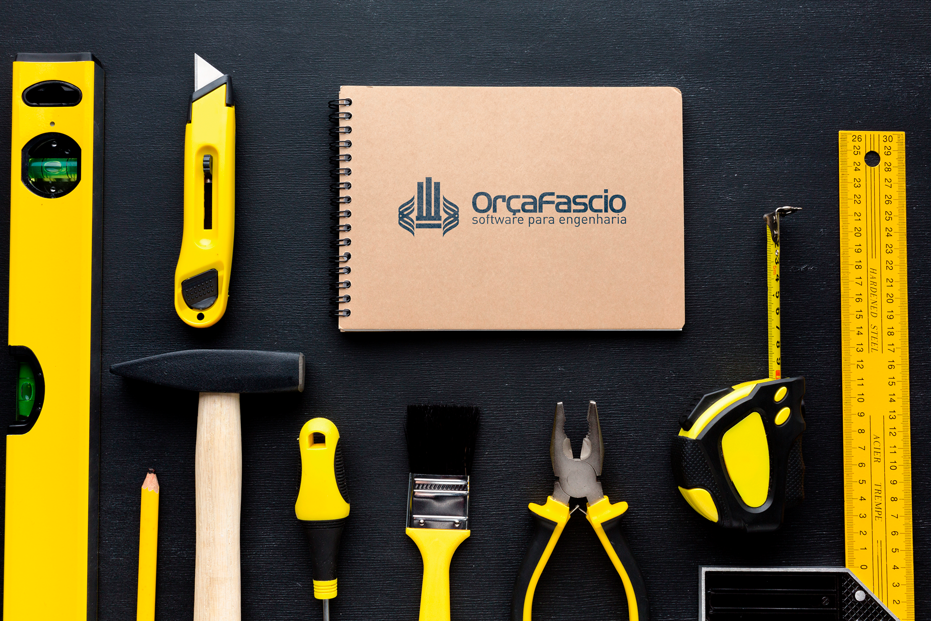 imagem com diversas ferramentas de engenharia e um caderno com o logo da orçafascio no centro